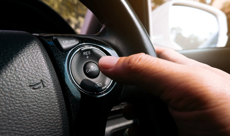 Finger pressing buttons on a steering wheel.